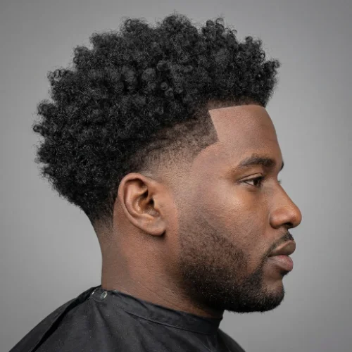 Low taper curly afro for men featuring natural afro curls on top and clean tapered sides